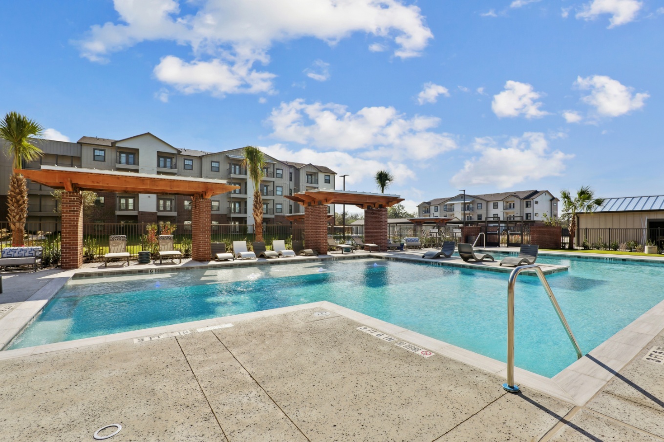 Swimming pool and sundeck with shaded lounge chairs at Brazos Oaks